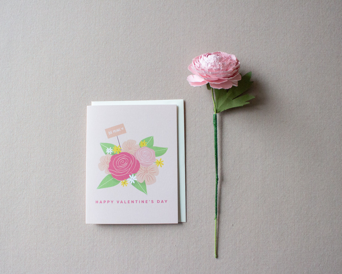 overhead shot of the be mine card and ranunculus flower